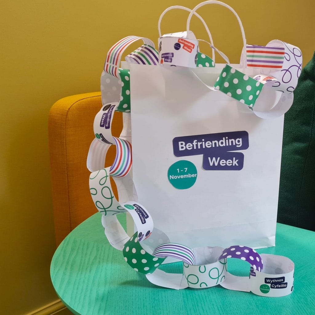 A bag with the Befriending Week logo, filled with colourful paper chains.